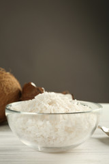 Glass bowl with coconut flakes on wooden table