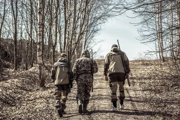 Papier Peint photo Chasser Group of men hunters going up on rural road during hunting season