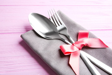 Table setting with silver cutlery and napkin on pink wooden background