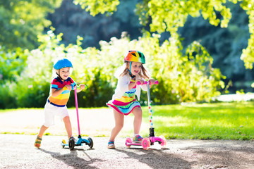 Kids riding scooter in summer park.