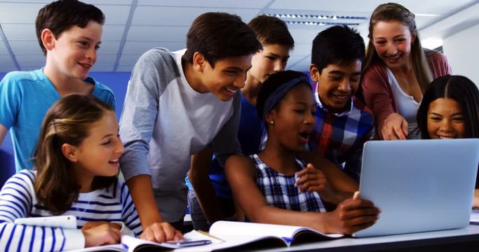 Group Of Mixed-race Students Using Laptop In Classroom