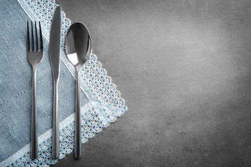 Table setting with silver cutlery and napkin on grunge background
