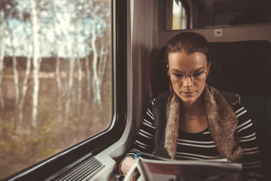 The young woman is on the train and watches through the window on the outside