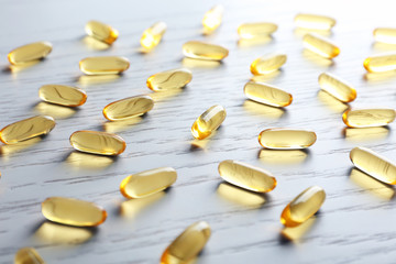 Fish oil capsules on white wooden table