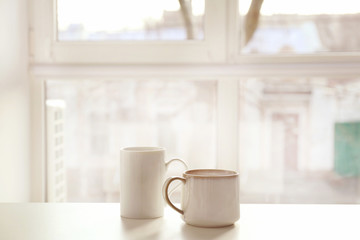 Cups of hot tea on table near window