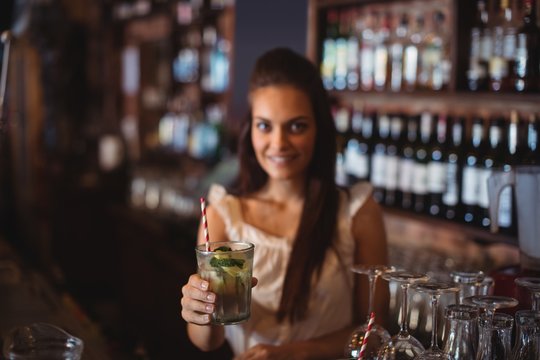 Portrait of female bar tender holding a glass of cocktail