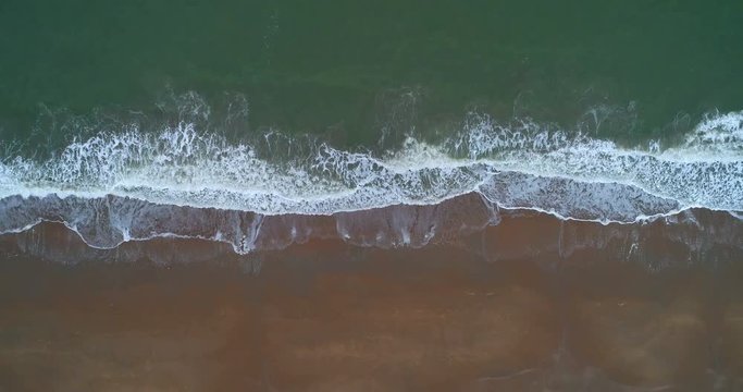 drone shot of beach with waves rolling in