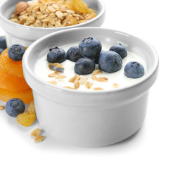 Bowl with tasty yogurt, flakes and berries on white background, closeup