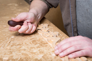woodcarver creates a furniture ornament. Woodcarver's hands, chisels, tools, wood-carved ornament.