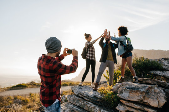 Young man taking pictures of his friends hiking