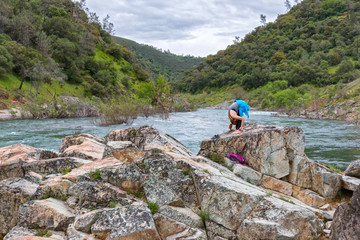 Girl Stretching on Rocks Near Fast River