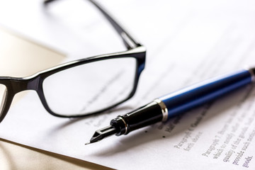 Fototapeta premium Signing the contract with pen and glasses in business work on office desk