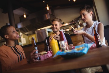 Happy friends interacting while having meal and beer