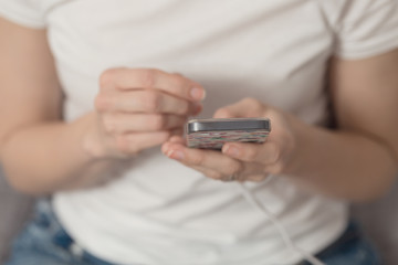 Young girl holding her phone and texting; phone connected to charger, instagram effect applied in post processing
