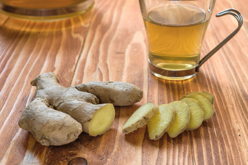 Ginger tea with ginger sliced on a wood table