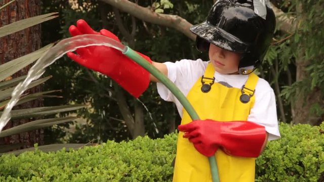 A boy dressed in a fireman sprays water all over himself.