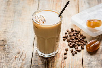coffee break with cold iced latte and beans on wooden table background