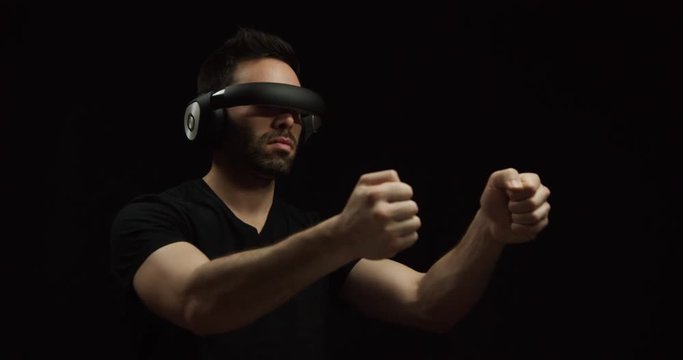 Man wearing futuristic virtual reality headset plays car driving game, on black