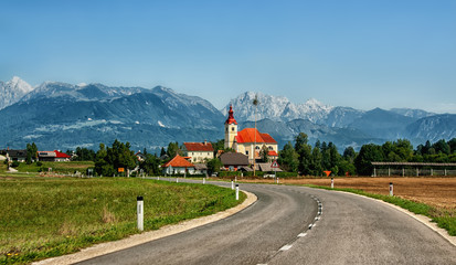 The European landscape where the road leads to the Church building on a background of mountains of...