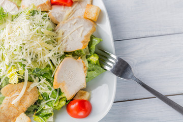Healthy green organic caesar salad close up on white plate and fork