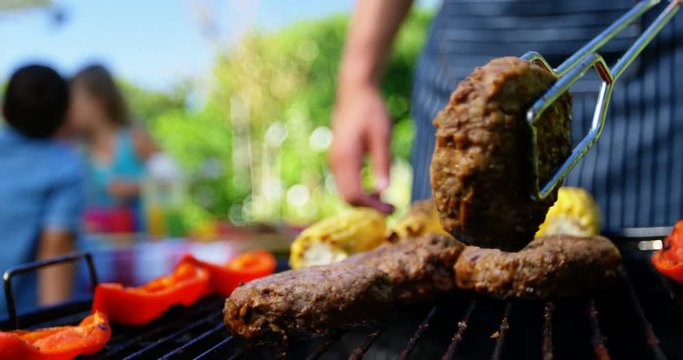 Mid section of man flipping meat on barbecue