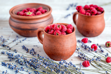 Obraz na płótnie Canvas raspberry in pottery and lavender flowers on rustic background