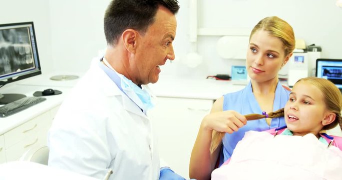 Dentist showing young patient how to brush teeth