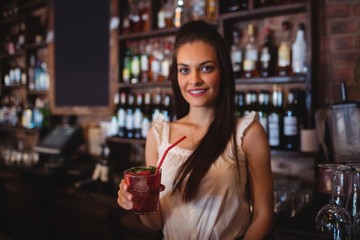Female bartender holding a cocktail drink at bar counter