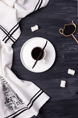 Black coffee in a white cup, vanilla bean and marshmallow on a dark background. Top view
