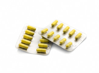 Yellow pills in a blister pack and scattered on a white background