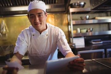 Chef holding digital tablet and an order list 