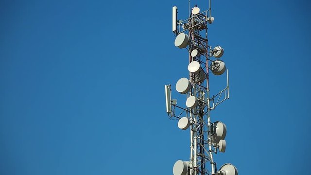Communication tower antenna on blue background. Cell phone telecommunication tower. Antennas of mobile phone communication, television, internet, radio, on blue sky background