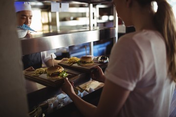 Chef passing tray with French fries and burger to waitress  - Powered by Adobe