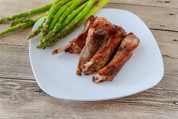 Roasted pork ribs and potato fries on white plate, close up
