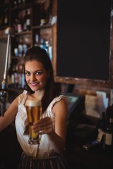 Female bar tender holding glass of beer