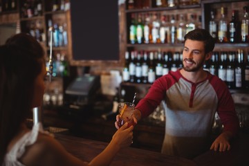 Female bar tender giving glass of cocktail to customer