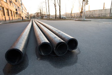 A lot of communication pipes on the pavement in the city, located on the left side of the frame, shot from a low point