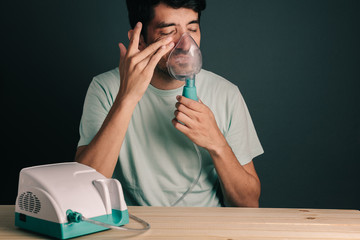 Portrait of man using domestic inhaler / nebulizer with sinusitis symptoms