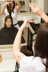 Hairdresser cutting dark hair using professional scissors