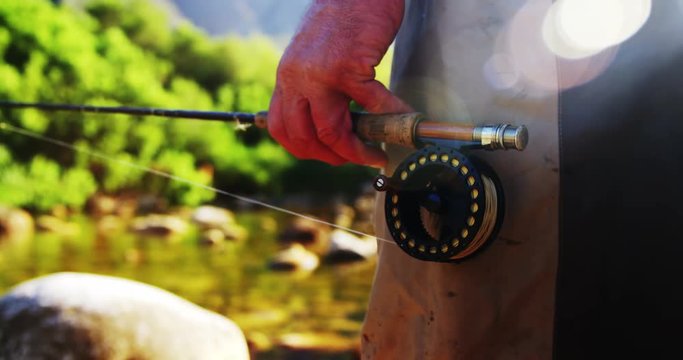 Fly fisherman standing in rock with fishing rod