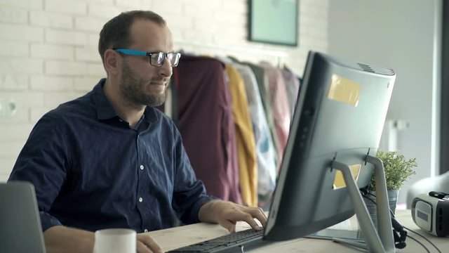 Young man working on pc computer sitting by table at home
