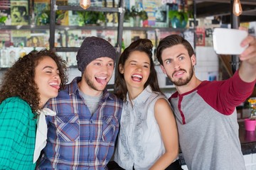 Friends making faces while talking selfie in restaurant