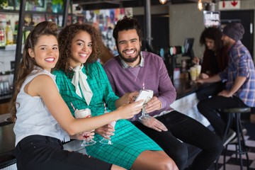 Cheerful friends talking about mobile and drinking