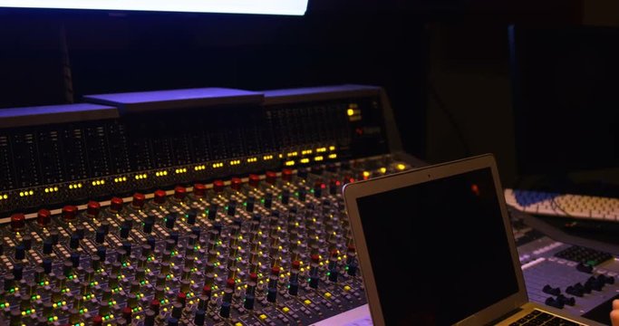 Audio engineers using laptop while mixing sound