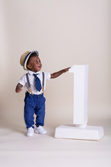Adorable one year old boy standing next to the number one 