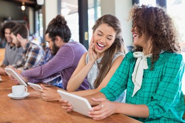 Friends using digital tablet while sitting in restaurant