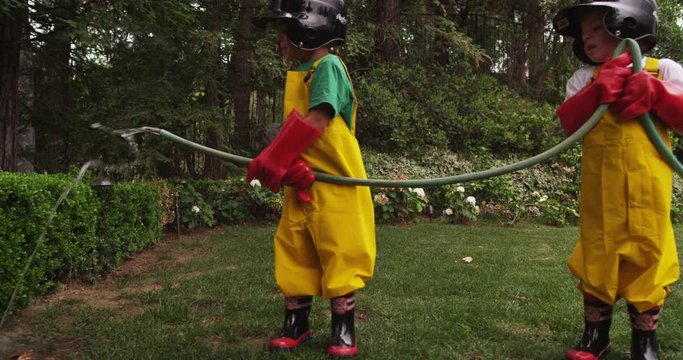 Slow motion, kids play with garden hose in backyard