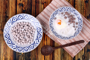 Purple potato dumplings with poached egg and coconut roll in sweet coconut cream .