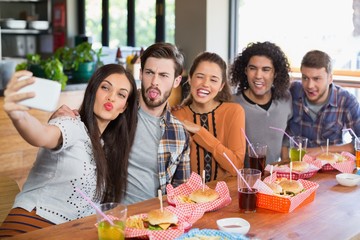 Woman taking selfie with friends in restaurant