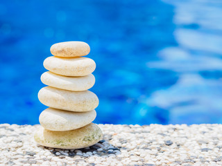 Fototapeta na wymiar Balance Stones stacked to pyramid in the soft blue water background to Spa ideas design or freedom and stability concept on rocks.